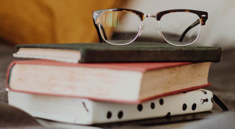 óculos apoiado em uma pilha de livros