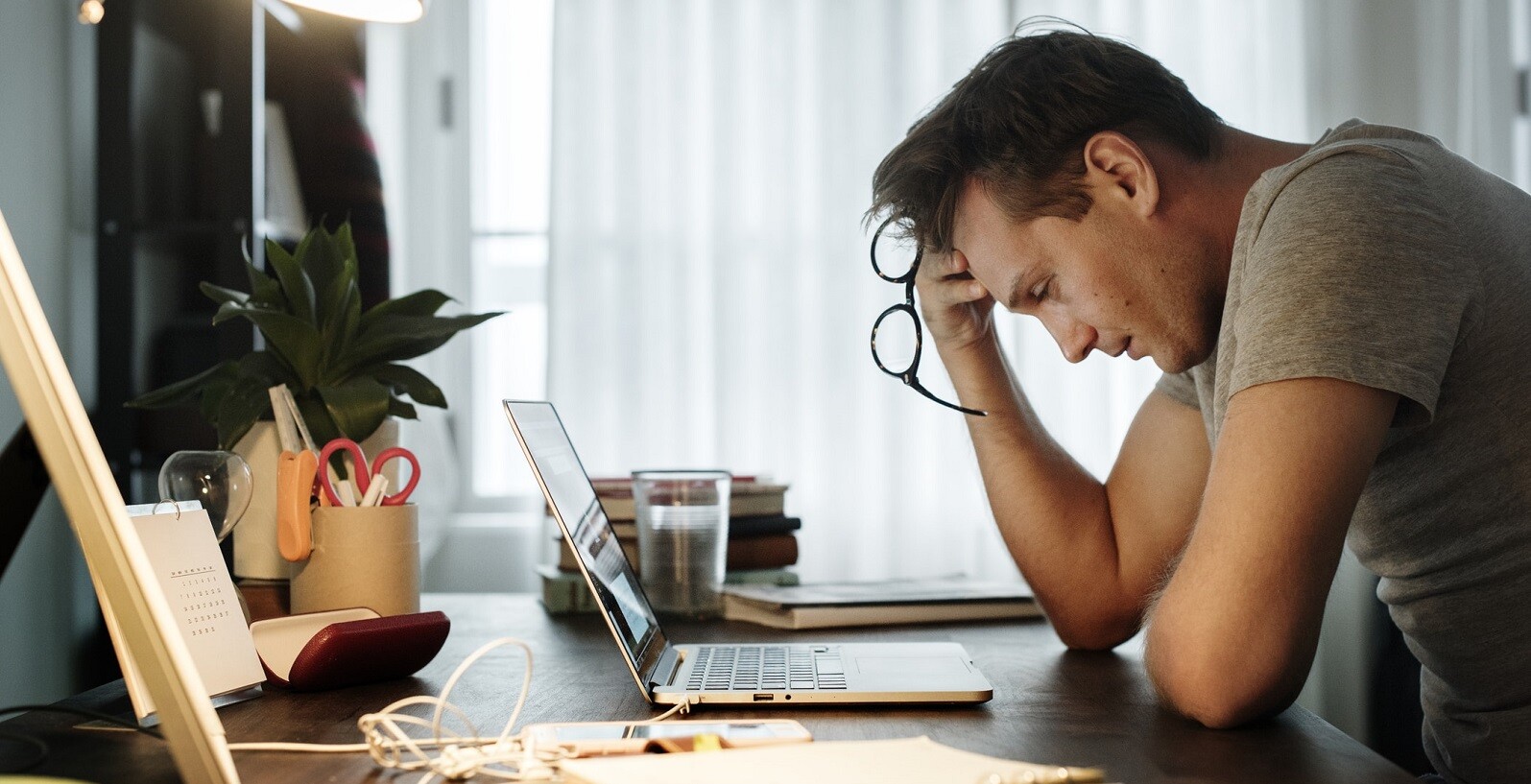 trabalho freelance - homem com a cabeça apoiada na mão, olhando pensativo para o computador