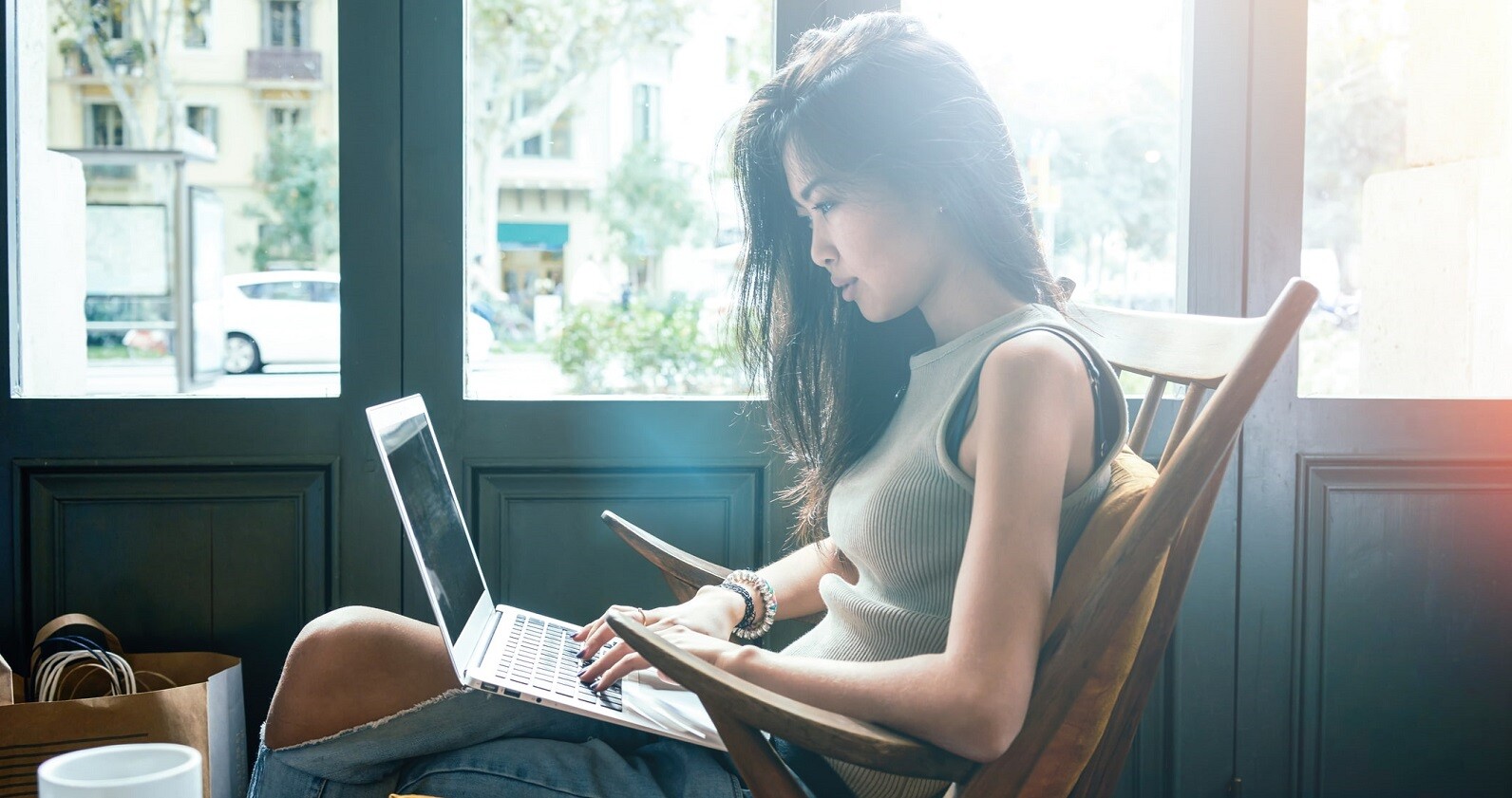 cursos gratuitos de marketing digital - foto mostra jovem mulher em um café, sentada em uma poltrona e com um computador no colo